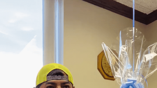 guy wearing yellow hat and orange shirt sitting at a desk
